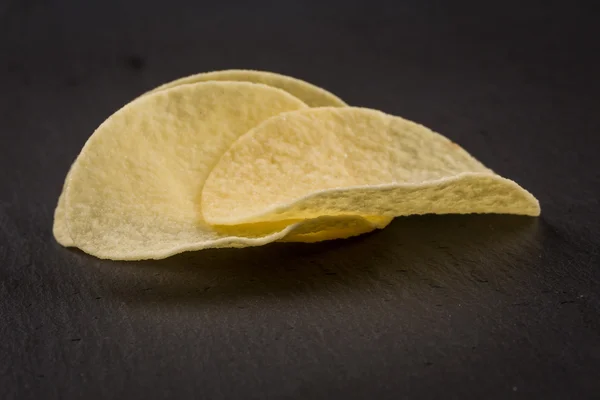 Kartoffelchips auf schwarzem Hintergrund — Stockfoto