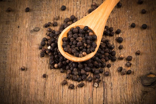 Pimienta negra sobre cuchara de madera — Foto de Stock