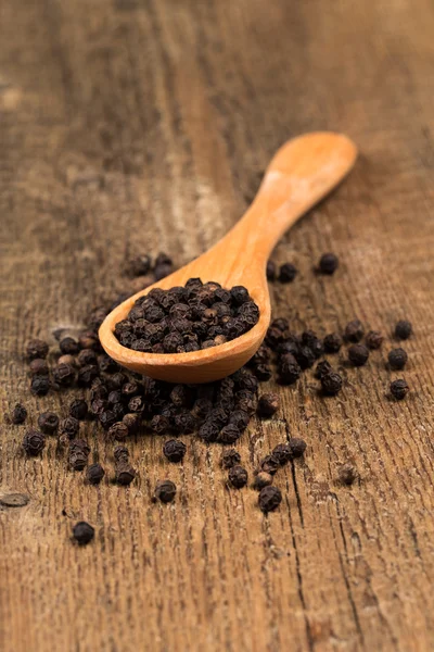 Black pepper on wooden spoon — Stock Photo, Image