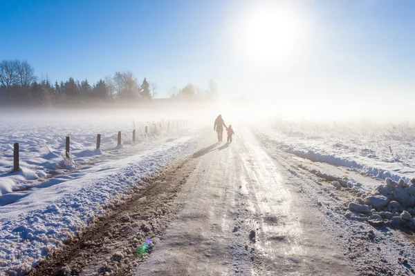 Mãe e criança na estrada nebulosa da neve — Fotografia de Stock