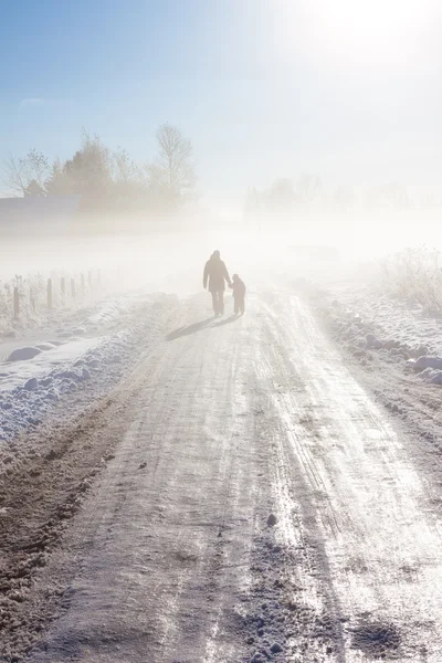 Mãe e criança na estrada nebulosa da neve — Fotografia de Stock