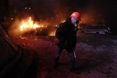 Otobüs yanan bir arka plan üzerine bir gaz maskeli adam. Kyiv, İngiltere
