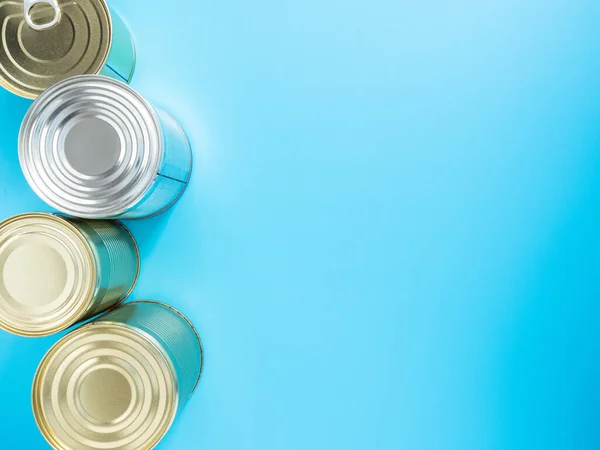 Food stocks for the duration of quarantine and isolation in the coronavirus and flu pandemic. Canned food in tin cans, isolated on a blue background, close-up, mockup, copyspace. Donation food.