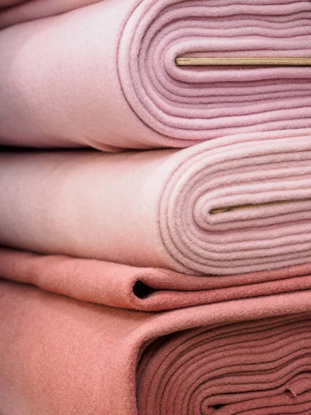 Rolls of warm dense fabrics in pastel colors, close-up. Trendy collection of monochrome fabrics, a new trend. Beautiful natural fabric lies in layers on store shelves for sale.