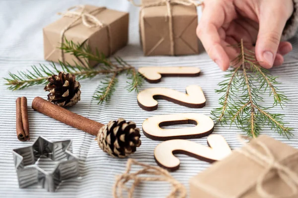 Gifts made of Kraft paper, Christmas tree branches, wooden numbers 2021, cones, festive atmosphere, close-up. Preparation for the new year, gift wrapping, natural materials.