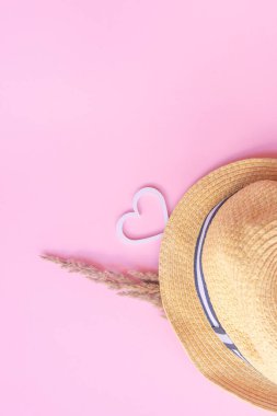 Pembe arka planda hafif hasır şapka ve kır çiçekleri. Yaz konsepti. Düz yatıyordu