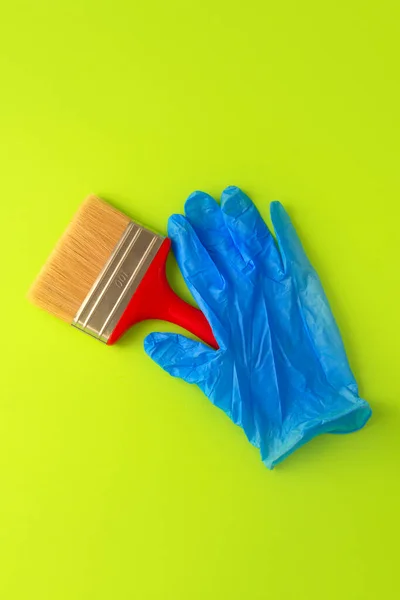 Kobieta Niebieskich Rękawiczkach Trzyma Czerwoną Szczotkę Malowania Zielonym Tle Koncepcja — Zdjęcie stockowe