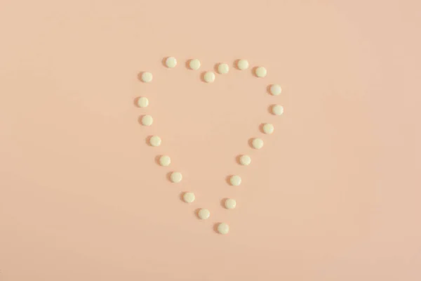 Hjärtat gjort av tabletter och piller på beige bakgrund. kopieringsutrymme för text. — Stockfoto