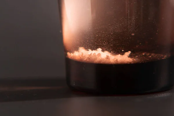 Effervescent tablet dissolving in a glass of water at black background