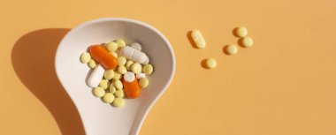 Beyaz kaşıkta çeşitli ilaç hapları, haplar ve kapsüller.