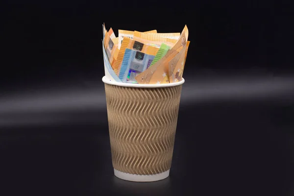 Euro banknotes in a coffee Cup on a black background. Finance