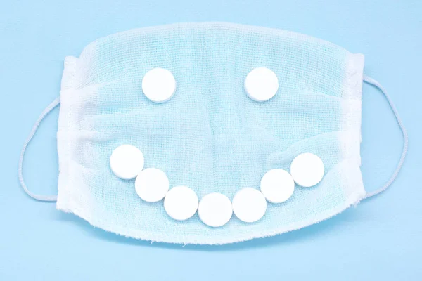 Ochranná maska a usmívající se obličej z bílých tablet. — Stock fotografie