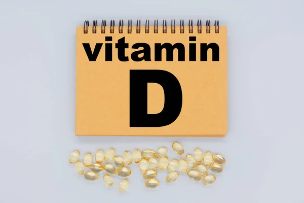 Vitamine D is geschreven op het bord en capsules op een blauwe achtergrond — Stockfoto