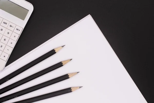 white calculator on black background, paper and pencils. Office desk. Business concept