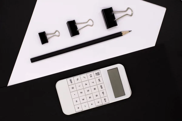 white calculator on black background, paper and pencils. Office desk. Business concept