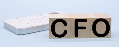 Muhasebe Müdürü Ahşap Bloklar Finans Müdürü ve beyaz hesap makinesi. Mavi arka planda tahta küplerin finans müdürü kısaltması. İş konsepti.