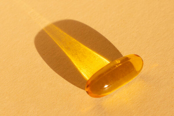 Омега 3 капсулы лежат и тени на бежевом фоне. Рыбий жир в таблетках. Медицинская поддержка и лечение. Биологически активные добавки