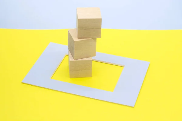 黄色背景上蓝色框架中的木制立方体 — 图库照片