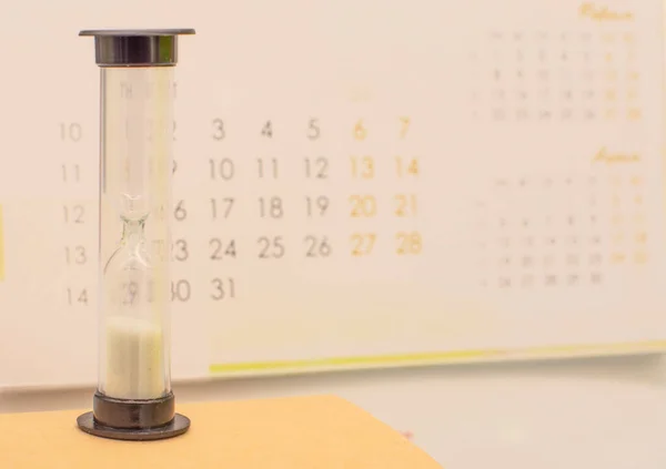 hourglass on the calendar background. The concept of time and planning