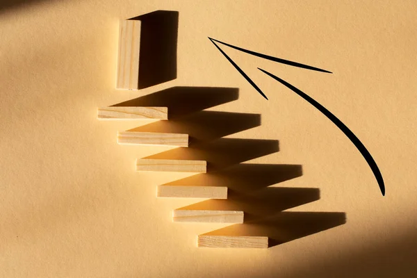 steps up from wooden blocks on a beige background. concept of resilience,development and achieving the goal