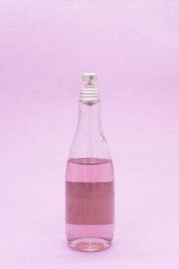 Pembe arka planda cam bir şişe vücut spreyi. Spa
