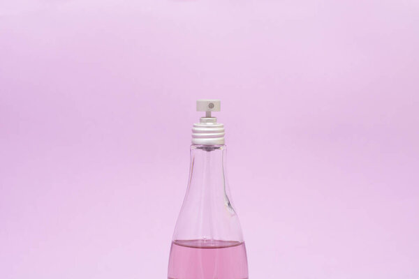 стеклянная бутылка спрея для тела на розовом фоне. СПА