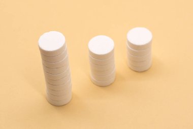 Bej arka planda bir yığın hap. Kümelenmiş beyaz haplardan oluşan büyüme grafiği - büyüyen pazar ve artan ilaç talebi ve onun yerine geçen.