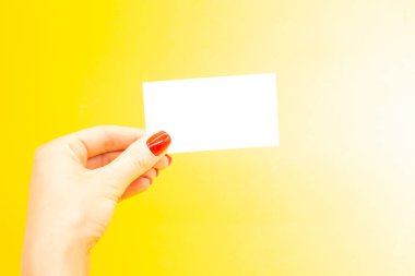 Modaya uygun manikürlü bir kadın eli kartvizit tutuyor. Yaz bahar tırnağı tasarımı.
