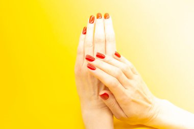 Güzel bir kadın eli ve sarı bir arka planda güzel bir manikür.