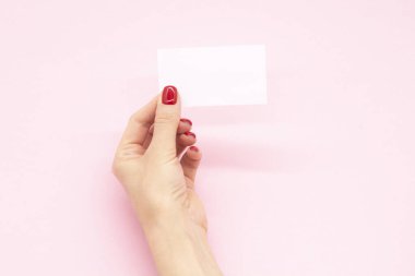 Modaya uygun manikürlü bir kadın eli kartvizit tutuyor. Yaz bahar tırnağı tasarımı.