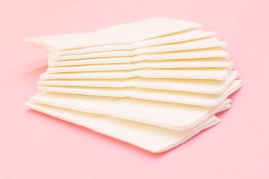 Pembe arka planda temiz kağıt peçeteler yığını.