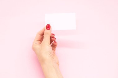 Modaya uygun manikürlü bir kadın eli kartvizit tutuyor. Yaz bahar tırnağı tasarımı.