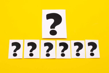 Sarı arka planda beyaz bir sayfa üzerindeki soru işareti. SSS frekansları soru, cevap, bilgi ve beyin fırtınası kavramları sorar