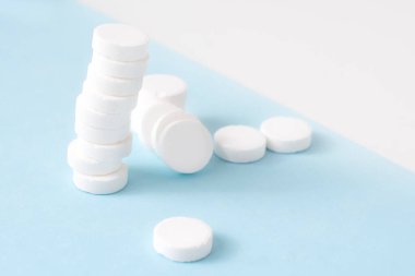 Mavi arka planda bir yığın hap. Kümelenmiş beyaz haplardan oluşan büyüme grafiği - büyüyen pazar ve artan beyaz hap talebi