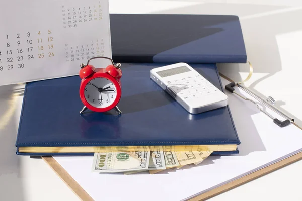 red round alarm clock, calculator, calendar and dollars. planning concept