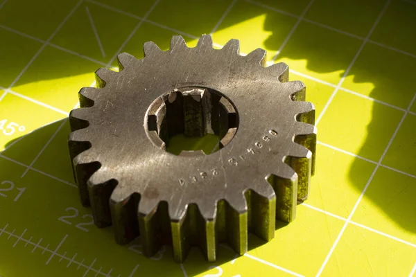 Pinion gear. Metal cog tooth wheel on a green background