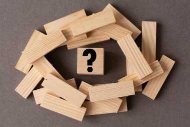 Tahta bloklar ve ortasında soru işareti olan tahta bir küp. İş stratejisi, problem çözme, meydan okuma veya engel kavramı.