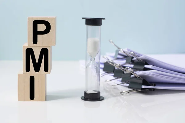 PMI yazılı tahta blokların yanında bir kum saati. PMI - Satın Alma Yöneticileri İndeksi