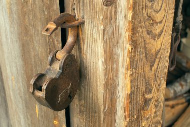 Ahır kapı kilidi eski ahşap duvarların arka planında asılı.