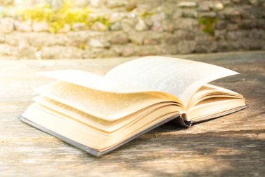 Tahta bir masanın üzerinde eski, açık bir kitap. Kitap oku.