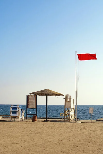 Bandeira Vermelha Cadeira Madeira Branca Fundo Céu Azul Mar Vermelho — Fotografia de Stock