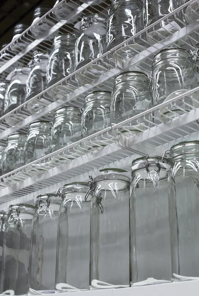 Platos de vidrio transparente y frascos en los estantes —  Fotos de Stock