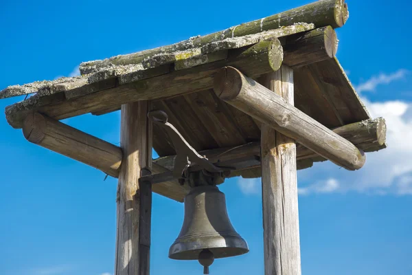 Campana antica sotto un tetto di legno contro il cielo blu — Foto Stock