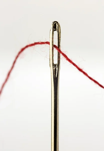 Sewing needle and red thread Stock Image