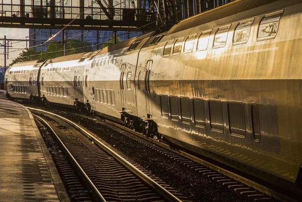 Passagerare tåg vid stationen i strålar från solen — Stockfoto