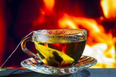 Cam bardak ateşten bir arka plan üzerinde siyah çay