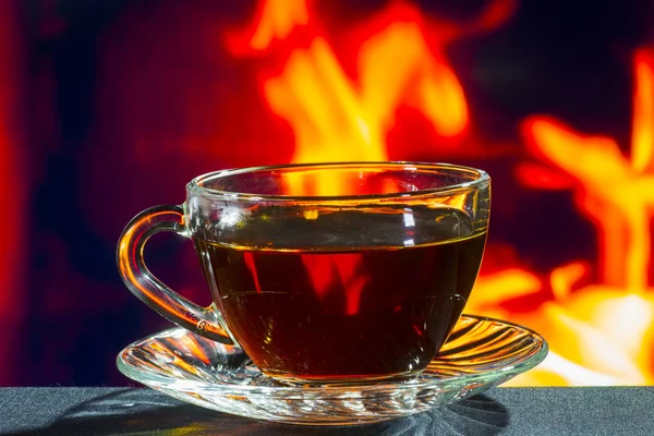 Glass cup of black tea on a background of fire — Stock Photo, Image