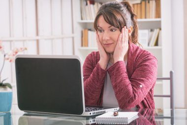 Orta yaş kadın laptop ile masada oturuyordu