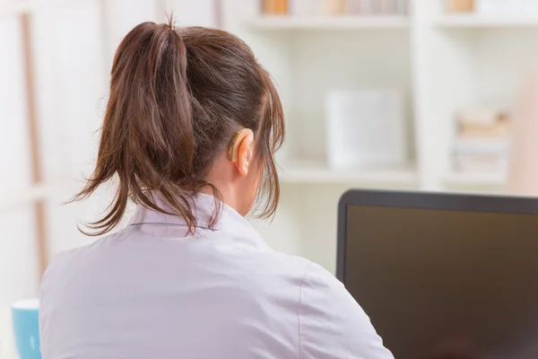 Mulher deficiente auditiva trabalhando com laptop — Fotografia de Stock