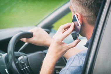 Arabada akıllı telefon olan adam